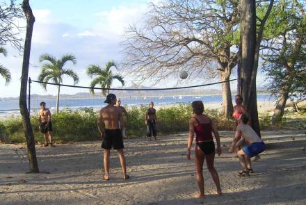 Spanish language students playing volleyball on the beach during sunset